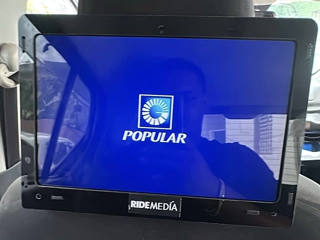 Pantalla Ride Media instalada en el reposacabezas con el logo de Popular